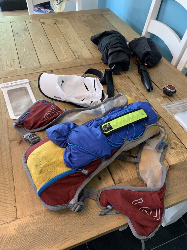 Photo of a selection of running kit on a table with pack, cap, and jacket clearly visible