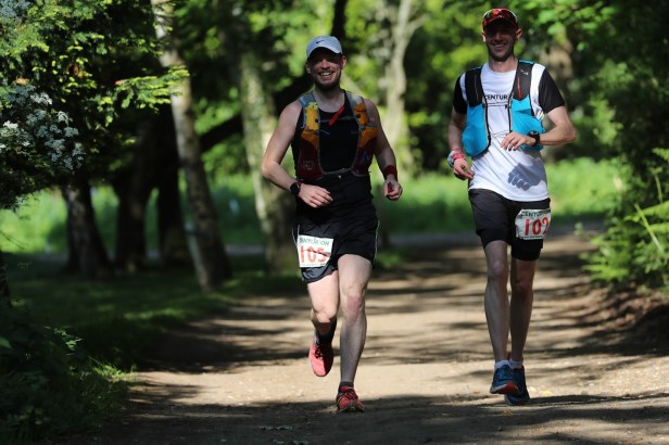 Photo of two runners running under tree shade smiling